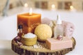 Home spa products on wooden disc tray: bar of soap, bath bomb, aroma bath salt, essential and massage oils, candle burning, rolled Royalty Free Stock Photo