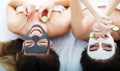 Home spa. Two women holding pieces of cucumber on their faces lying the bed. Royalty Free Stock Photo