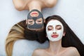 Home spa. Two women holding pieces of cucumber on their faces lying the bed. Royalty Free Stock Photo