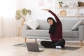 Home sport for muslim women. Arabic girl practicing online yoga with laptop