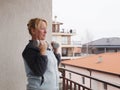 Home sports training, an adult woman shakes her biceps with dumbbells on the balcony
