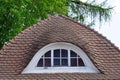 Home sweet home. Curved tiled roof and a round dormer window with lattice windows