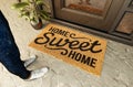 Home Sweet Home doormat and feet of a man standing on the porch at the front door Royalty Free Stock Photo