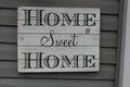 Home Sweet Home sign weathered and hanging on a house.