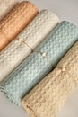 Home towels made of natural muslin in pastel shades are folded neatly in a row and decorated with a rope with a bead