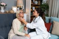 During a home visit to an elderly patient, a young endocrinologist doctor checks her thyroid gland by feeling her neck with her