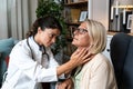 During a home visit to an elderly patient, a young endocrinologist doctor checks her thyroid gland by feeling her neck with her