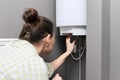 Home water heater, woman regulates the temperature on an electric water heater Royalty Free Stock Photo