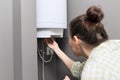 Home water heater, woman regulates the temperature on an electric water heater Royalty Free Stock Photo