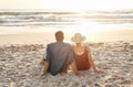 Home is where the waves crash. Rearview shot of a middle aged couple watching the sunset on the beach. Royalty Free Stock Photo