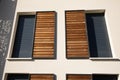 home windows with modern wooden brown sliding shutters in house beige new facade apartment building Royalty Free Stock Photo