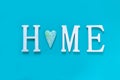 Home, wooden text with heart shape decor on blue background. Concept of building houses, choosing your own house, mortgage, buying