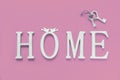 Home, wooden text with heart shape decor on pink background. Concept of building houses, choosing your own house, mortgage, buying