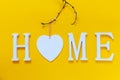 Home, wooden text with heart shape decor on yellow background. Concept of building houses, choosing your own house, mortgage,
