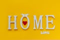 Home, wooden text with heart shape decor on yellow background. Concept of building houses, choosing your own house, mortgage,