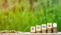 Home word on stack of coins and a pile of golden coins on wooden table.