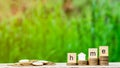 Home word on stack of coins and a pile of golden coins on wooden table.