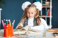 Home work is a difficult task test first grade back to school concept. girl with pigtails and bows in a white blouse shirt leafing