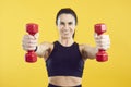 Close up of two red dumbbells in hands of sporty woman isolated on vivid yellow background. Royalty Free Stock Photo