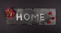 Home written with White Gemstones on a stone background surrounded by red flowers. Home Sweet Home Concept