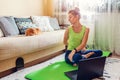 Home yoga workout during coronavirus lockdown. Seated spinal twist pose. Woman training using mat by cat. Royalty Free Stock Photo