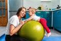 Home yoga. A young mother plays with her baby lying on a fit ball. The concept of fitness with children at home Royalty Free Stock Photo