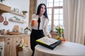 Young woman came home after work, putting newspaper and portfolio on table