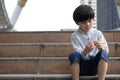 Homeless Asian child sitting alone on the stairway in the street. Poor, sad, scared and alone Royalty Free Stock Photo