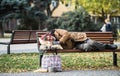 Homeless beggar man with a bag lying on bench outdoors in city, sleeping. Royalty Free Stock Photo