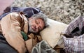 Homeless beggar man lying on the ground outdoors in city, sleeping. Royalty Free Stock Photo