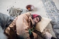 Homeless beggar man lying on the ground outdoors in city, sleeping. Royalty Free Stock Photo