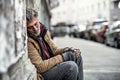 Homeless beggar man sitting outdoors in city asking for money donation, sleeping. Royalty Free Stock Photo