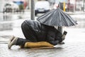 Homeless beggar with umbrella in the rain