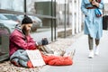 Homeless begging money to a passing by woman