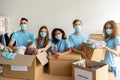 Homeless care concept. Young volunteers in medical face masks sorting clothing donations, working in charity center Royalty Free Stock Photo