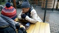 Homeless couple, man and woman eating leftovers from a table in a street cafe