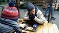 Homeless couple, man and woman eating leftovers from a table in a street cafe