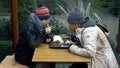 Homeless couple, man and woman eating leftovers from a table in a street cafe