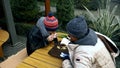 Homeless couple, man and woman eating leftovers from a table in a street cafe