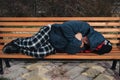 homeless dirty elderly old Caucasian man lies sleeping on park bench in autumn Royalty Free Stock Photo