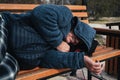 homeless elderly old man lies sleeping on park bench in autumn