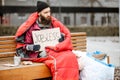 Homeless beggar on the bench near the business center