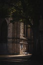 Homeless man asleep on the sidewalk beside a church and behind a tree