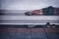 Homeless man dirty sleeps on the street in the shadow of the building Royalty Free Stock Photo