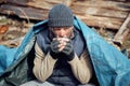 A homeless man drinks hot tea near the ruins, helping poor and hungry people during the epidemic