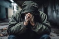 Homeless man in a jacket and hoodie crying covering his face with his hands. Generative AI