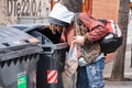 Homeless man picks things up from a dumpster