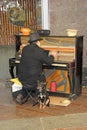 Homeless man playing piano on street with stray dog