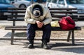 Homeless man, Poor homeless man or refugee sleeping on the wooden bench on the urban street in the city with bags of clothes and j Royalty Free Stock Photo
