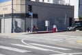 A homeless man with a shopping cart on the corner of Yucca Street with a woman wearing red pants crossing the street in Hollywood